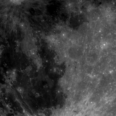 A zoomed in section of the Moon. The surface is shades of light and dark grey with many craters that range in size. There are some very dark, almost patches, large patches on the image left.