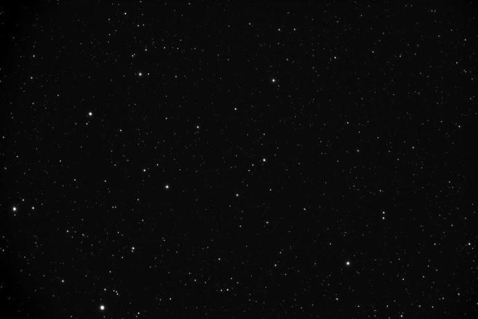 A black sky with lots of bright stars as white dots randomly placed across it. The stars are varied in size, and some of them appear slightly redder than others.